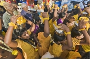 Pilgrims in holy yellow outfits carry pots of milk on their heads