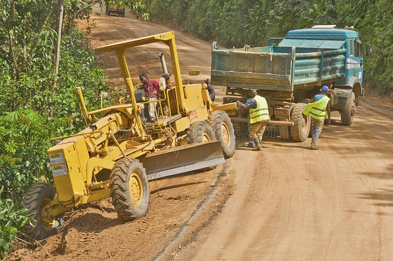 A heavy truck helps to pull a stranded grader out of trouble on a jungle logging road.