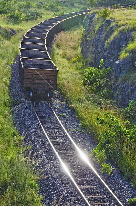 A heavily laden coal train rounds a corner at sunset in Lope National Park.