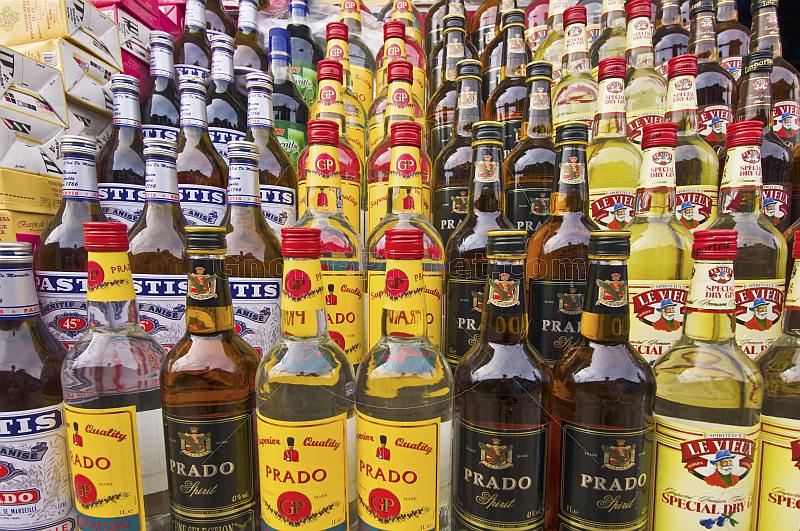 A display of imported and local liquor and spirit drinks bottles on a market stall.