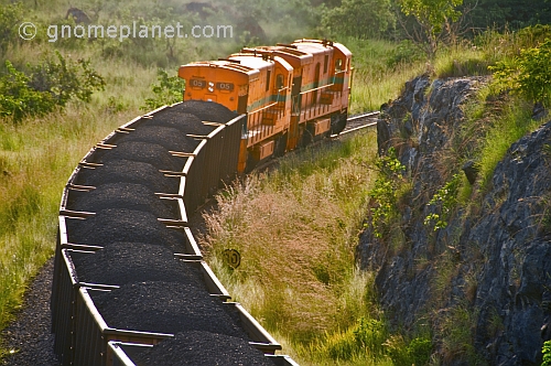 Two diesel locomotives pull a heavily laden coal train through Lope National Park.