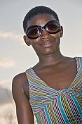Gabonese teenager with short hair and sunglasses wears a striped dress.
