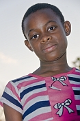 Gabonese teenager with short hair wears a striped blue white and pink dress.