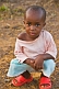 Young Gabonese girl with short hair in a light pink shirt and red shoes.