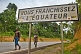 Image of Two Gabonese men walk past the road sign marking the Crossing of the Equator.