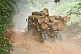 Image of A logging truck loaded with tropical hard woods drives along a dusty jungle road.