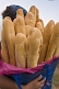 Image of Woman in headscarf carries a shopping bag full of French baguette bread sticks.