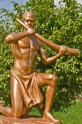 Bronze painted statue of man in loincloth holding a tusk of ivory.