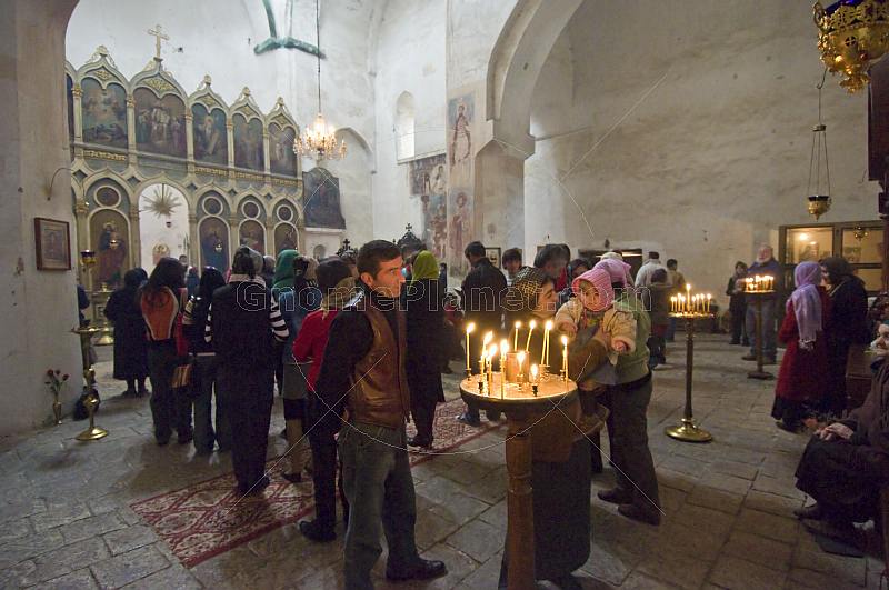 Eastern Orthodox worshippers gather for mass at the Ananuri Monastery, whilst a young mother shows the candlelight to her baby.