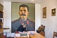 Image of The Director of the Joseph Stalin museum prepares the visitors book in front of a huge portrait of Uncle Joe.