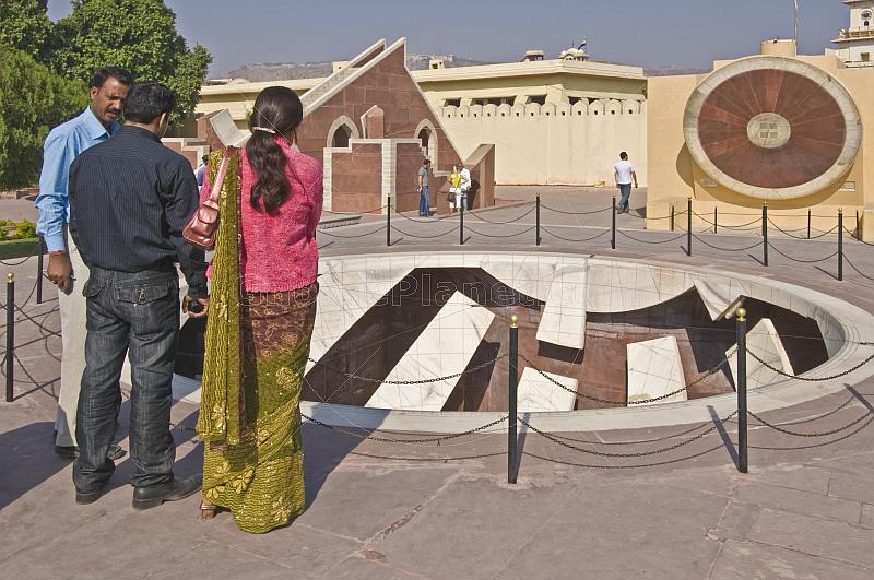 A guide explains details of one of the astronomical instruments at the Jantar Mantar Observatory to an Indian couple.