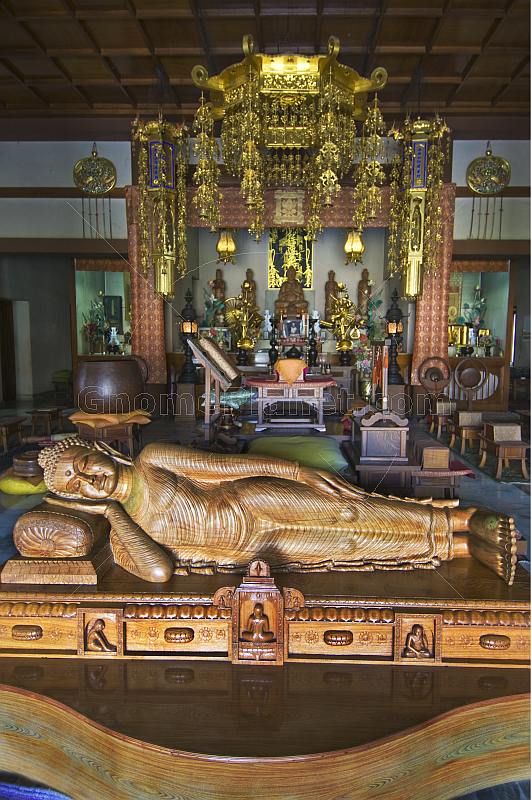 Wooden reclining Buddha statue in front of the altar of the Japanese Temple in Sarnath.
