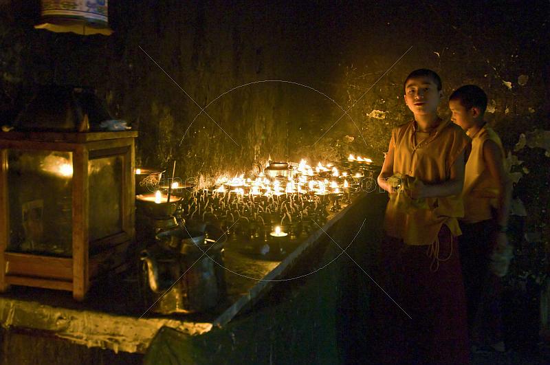 Two young trainee Buddhist monks prepare the oil lamps for the Enchey Monastery.