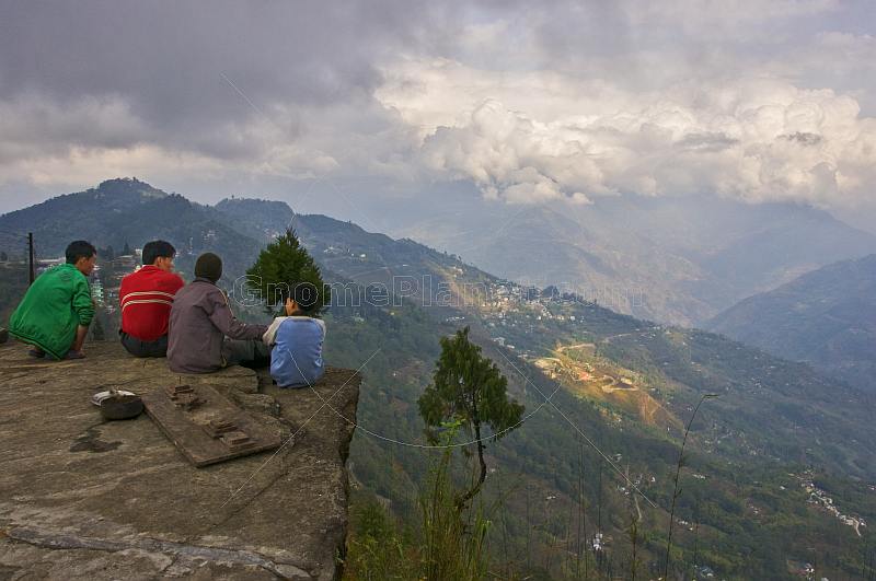 Four boys at the Sangachoeling Monastery look over a stormy valley as the sun breaks through the clouds.
