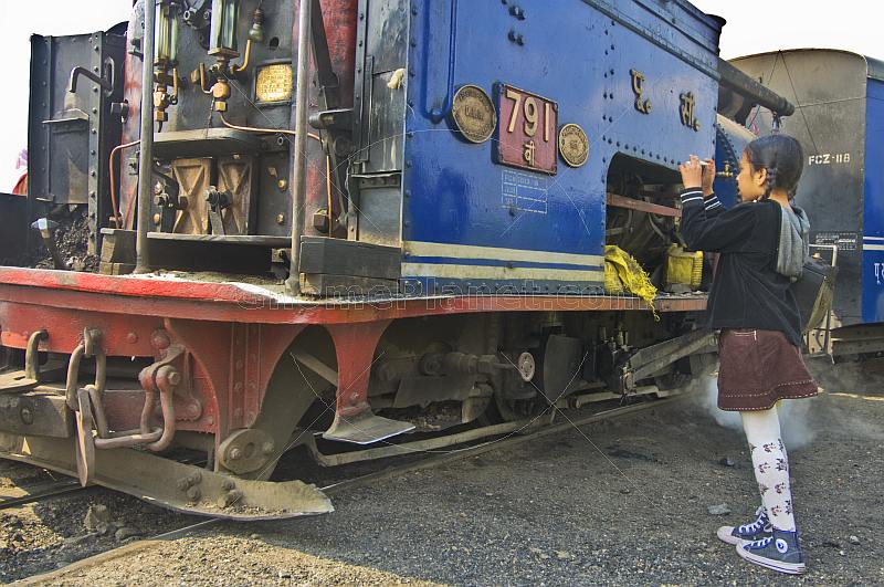 Small Indian girl snaps a photo of a steam locomotive on the Himalayan Mountain Railway, at the Batasia Loop.
