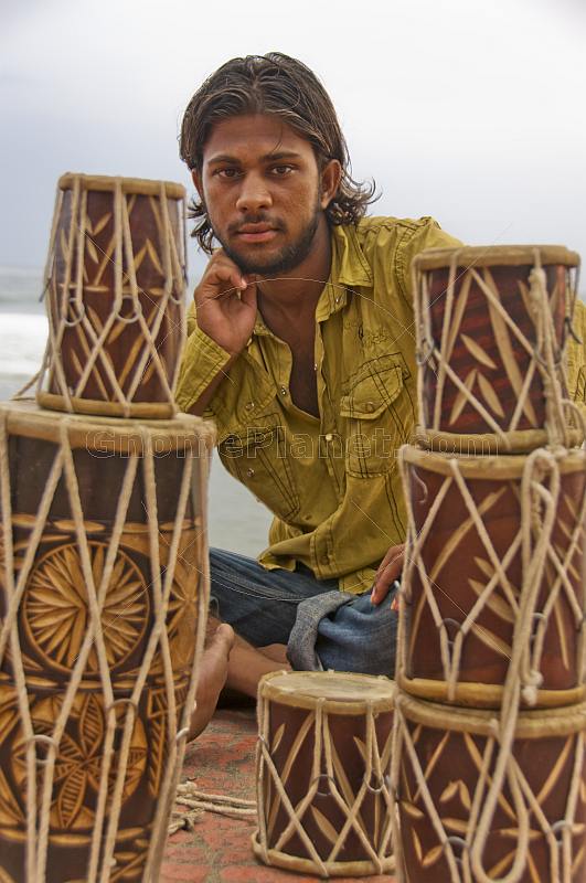 A young Indian man selling drums.