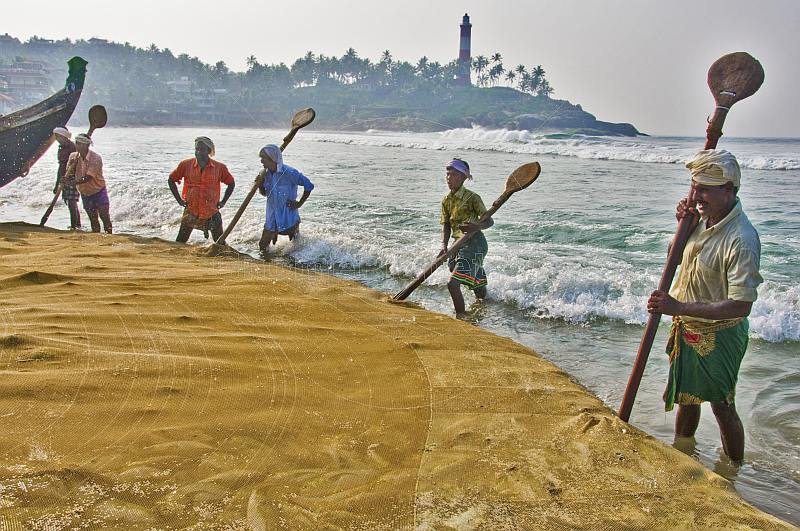 Fishermen use their oars to stop the fishing net getting washed back out to sea.