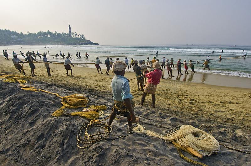 Fishermen haul their fishing net on to the beach.