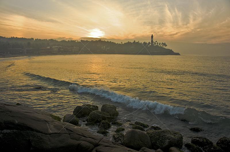 Dawn rises over Lighthouse Beach as waves break on the rocks.