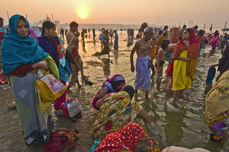 Male and female pilgrims prepare for ritual bathing in Ganges river at dawn.