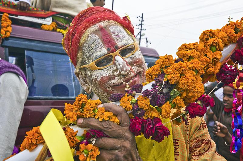 Hindu holy man with whitened face and orange glasses poses for the camera.