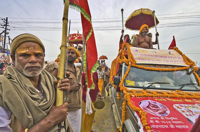 Hindu man holds flag for decorated Sadhu Truck in Kumbh Mela  parade.