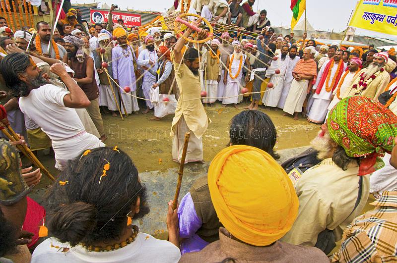Acrobat with revolving weights clears a path through Hindu crowds in the procession.