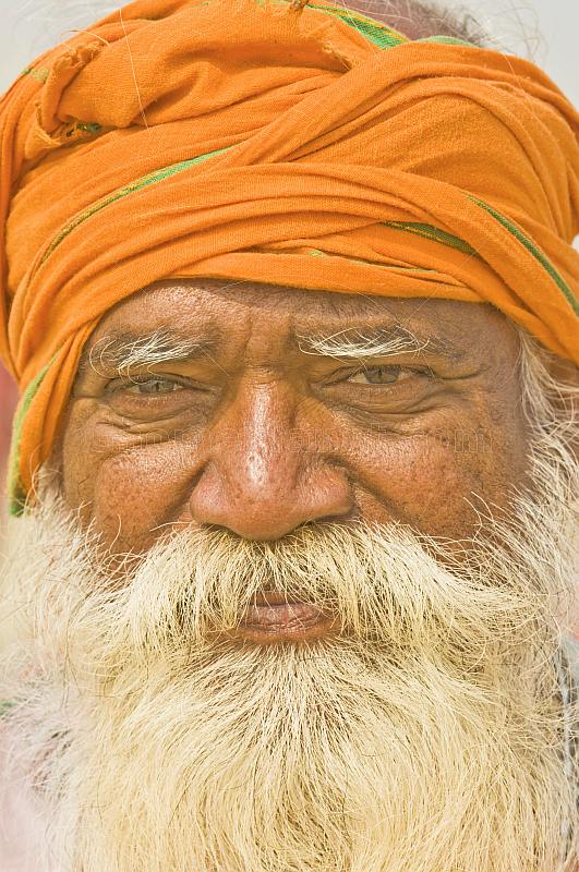 Smiling elderly Hindu Holy Man with orange turban and flowing white beard at Kumbh Mela.