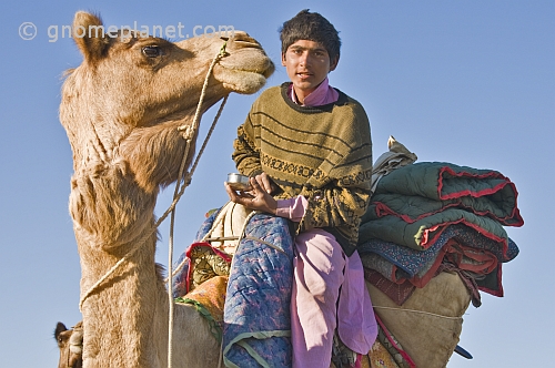 A young camel-driver enjoys an early morning cup of tea.