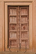 Ancient brown wooden door with blacksmith-made iron chains.
