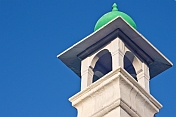 White stucco minaret with green cupola.