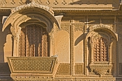 Richly-carved sandstone balcony with studded wooden doors on a havelli in the old quarter.