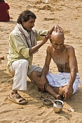 A barber shaves a Pilgrims head with a traditional cut-throat razor, on the dried-up bed of the Phalgu River, near the Vishnupad Temple.