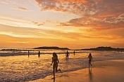 Western children run along the beach at sunset.