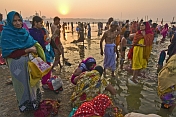 Male and female pilgrims prepare for ritual bathing in Ganges river at dawn.