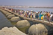 Mass crowds of Indian Hindu pilgrims cross pontoon bridge over Ganges river.