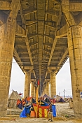 Colorful Kumbh Mela festival tents under concrete  pillars of the Lal Bahadur Shastri Bridge.