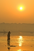 Woman In Sari Walks Through Ganges River Shallows At Dawn For A Ritual Bath