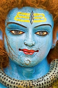 Cracked blue face of clay statue of god Shiva at Kumbh Mela Hindu religious festival.