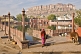 Image of An old woman walks away from the Gulab Sagar, with the Meherangarh Fort in the distance.