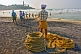 Image of Indian fishermen wearing lunghis haul in their nets from the beach.