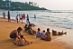 Image of Indian families play in the waves on Leela Beach at sunset.