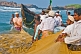 Image of Fishermen struggle to haul their fishing net through the surf.