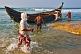 Image of Fishermen bring their boat in through the surf.