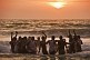 Indian boys dance in the waves at sunset.