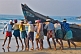 Image of Fishermen strain to launch their fishing boat into the surf.