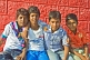 Image of Four Indian schoolboys in colored shirts pose for their photograph.