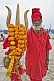 Image of Hindu holy man dressed in red with marigold decorated brass trident for Lord Shiva.