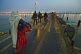 Pilgrims cross Ganges river pontoon bridge in pre-dawn light to join Kumbh Mela festival.