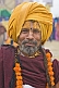 Smiling Hindu Holy Man with saffron-colored turban and marigold flower garlands.